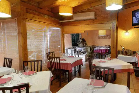 Comedor del Restaurante La Venta en Fuensaldaña, con vigas de madera, mesas con manteles rojos y blancos y sillas de madera