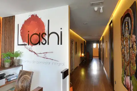 Entrada del Centro Liashi en Valladolid, con el logotipo del centro en la pared y un pasillo de suelo de madera con luz cálida