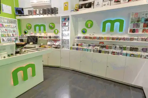 Interior de la tienda mmMimóvil en Ceuta, con el mostrador blanco, el logotipo verde en forma de «m» y estanterías llenas de fundas para móviles